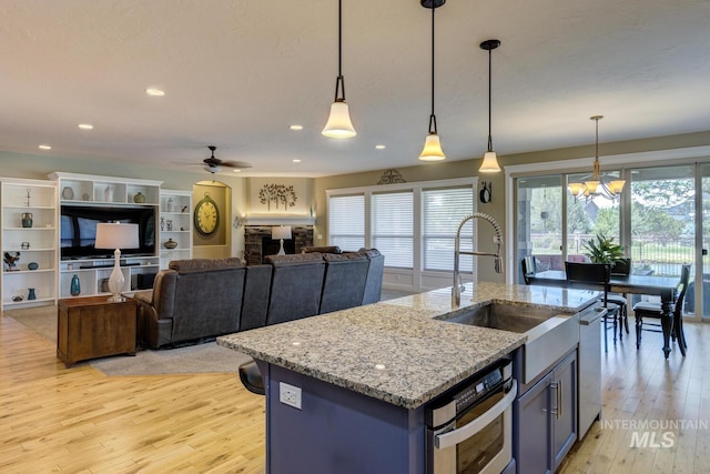 3214 S Arctic Fox Ave, Eagle, ID 83616 - kitchen featuring light wood-style flooring, stainless steel appliances, ceiling fan, pendant lighting, and light stone countertops