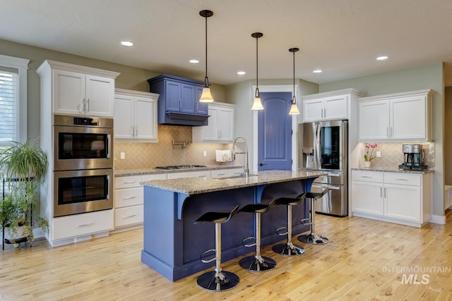 3214 S Arctic Fox Ave, Eagle, ID 83616 - kitchen featuring appliances with stainless steel finishes, tasteful backsplash, light wood-type flooring, a kitchen breakfast bar, and recessed lighting