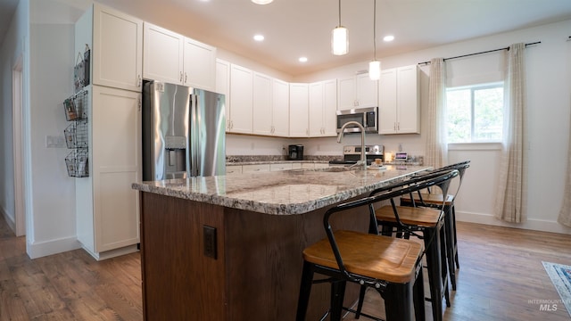 1147 Driscoll Ridge Rd, Troy, ID 83871 - kitchen featuring appliances with stainless steel finishes, baseboards, wood finished floors, light stone countertops, and white cabinets
