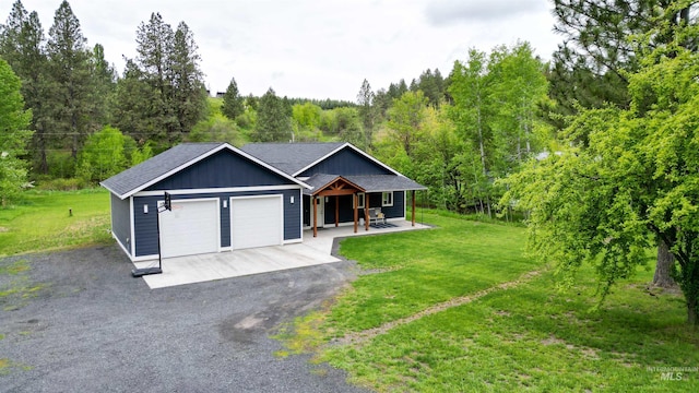 1147 Driscoll Ridge Rd, Troy, ID 83871 - view of front of house featuring covered porch, an attached garage, a front yard, asphalt driveway, and a view of trees