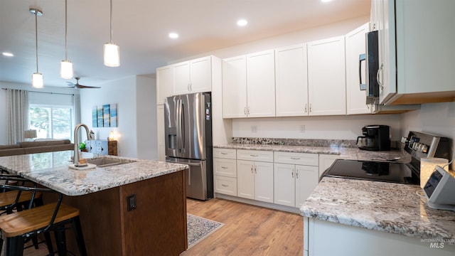 1147 Driscoll Ridge Rd, Troy, ID 83871 - kitchen featuring appliances with stainless steel finishes, a sink, a breakfast bar, white cabinetry, and light wood-style floors