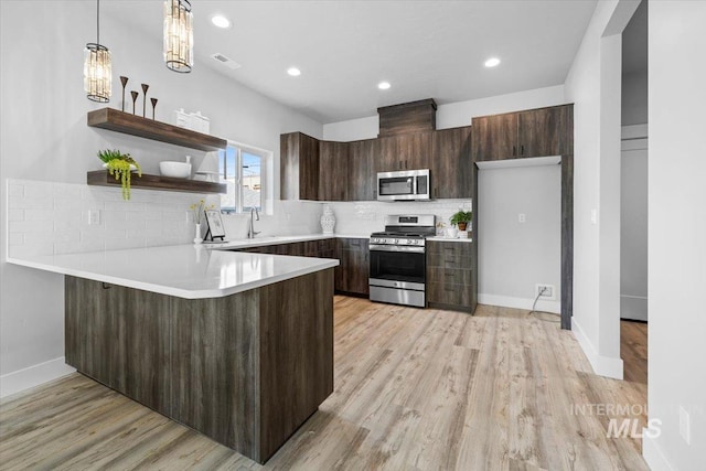 kitchen with light hardwood / wood-style floors, decorative light fixtures, stainless steel appliances, and decorative backsplash