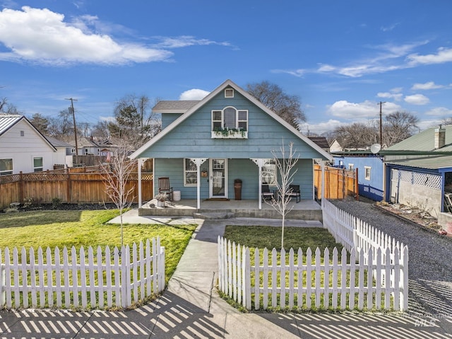 bungalow featuring a front lawn, fence, and a porch