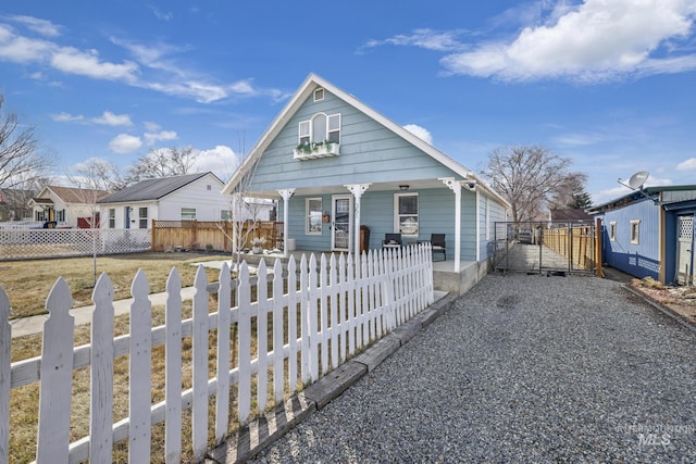 bungalow-style house featuring covered porch, a fenced front yard, a gate, and a residential view