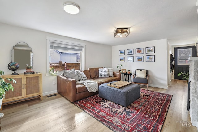 living area with wood finished floors, visible vents, and baseboards