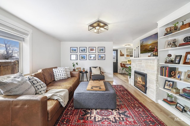 living area with a stone fireplace and light wood finished floors