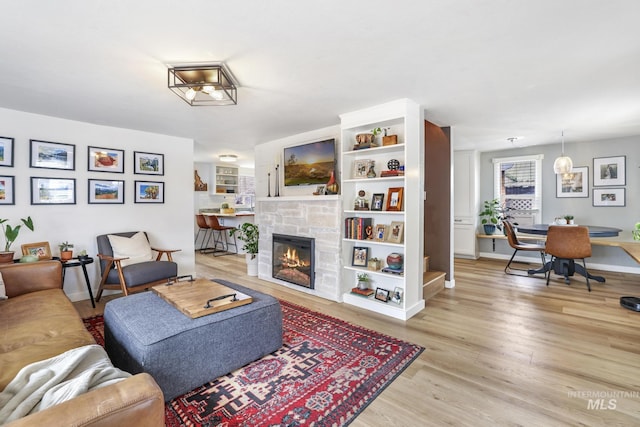 living room with light wood-style floors, a healthy amount of sunlight, a fireplace, and baseboards