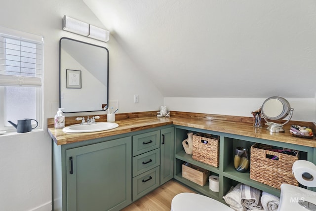 bathroom with vaulted ceiling, toilet, wood finished floors, and vanity