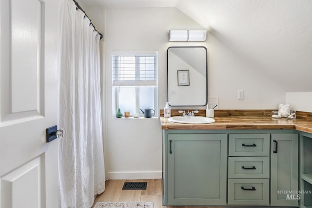 bathroom with lofted ceiling, visible vents, vanity, and wood finished floors