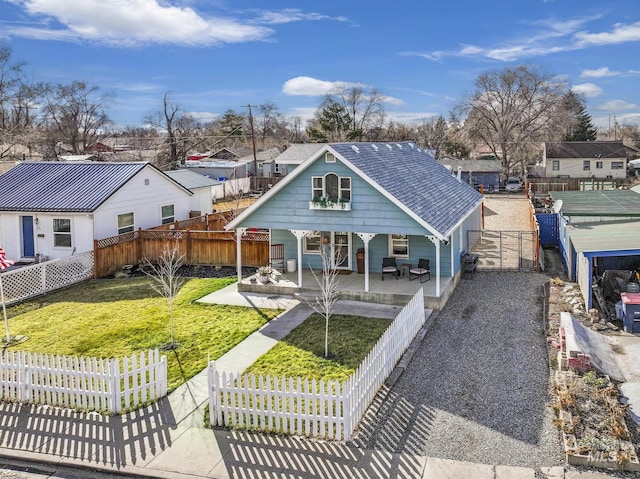 back of house featuring a shingled roof, covered porch, a lawn, a fenced backyard, and driveway