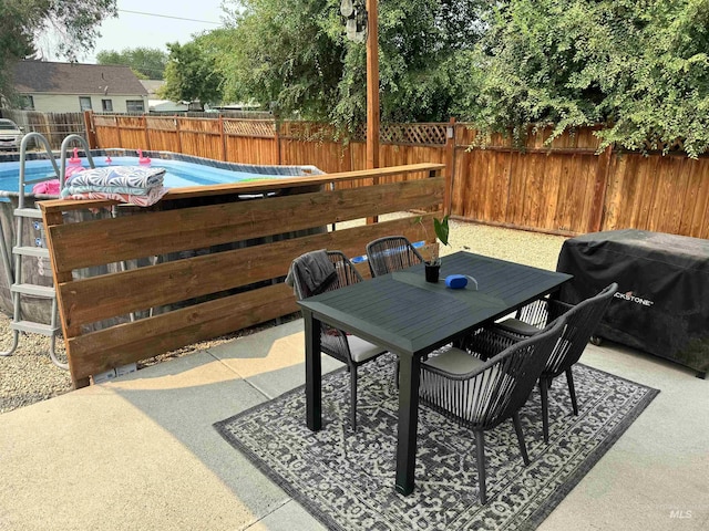 view of patio with outdoor dining area, area for grilling, fence private yard, and a fenced in pool