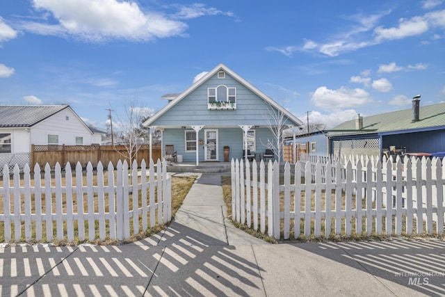 shotgun-style home with a porch and a fenced front yard