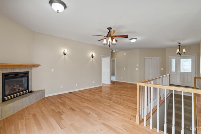 1141 Liberty Dr, Clarkston, WA 99403 - unfurnished living room featuring light wood-style floors, a tiled fireplace, baseboards, a ceiling fan, and a chandelier