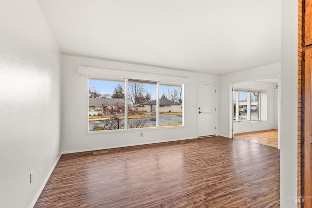 unfurnished living room featuring wood finished floors, visible vents, and baseboards