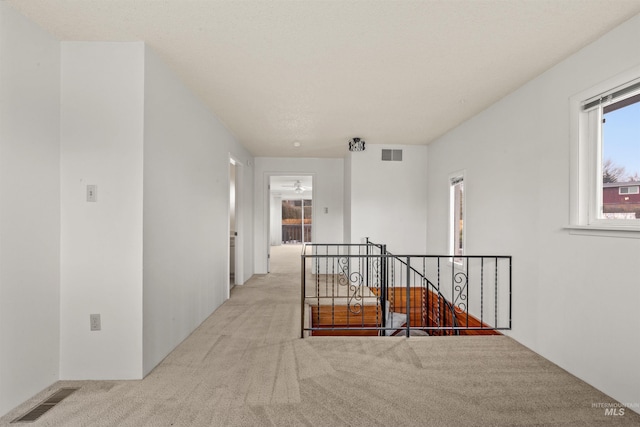 hall featuring carpet floors, an upstairs landing, and visible vents