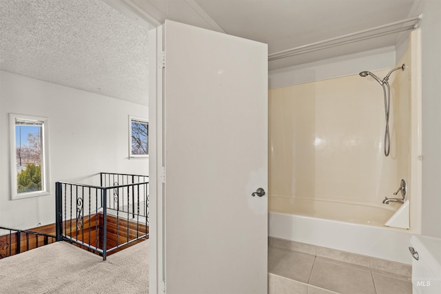 bathroom featuring a textured ceiling, bathtub / shower combination, and tile patterned floors