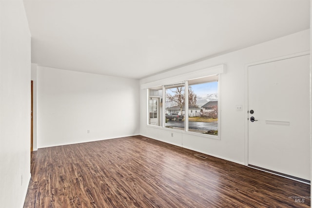 empty room featuring dark wood-style floors and visible vents