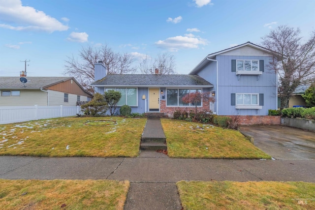 view of front facade featuring brick siding, a front yard, and fence