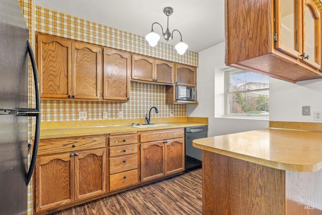 kitchen with dark wood-type flooring, a sink, light countertops, black appliances, and brown cabinetry