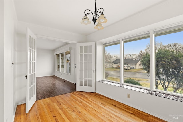 interior space with a chandelier, french doors, hardwood / wood-style floors, and baseboards