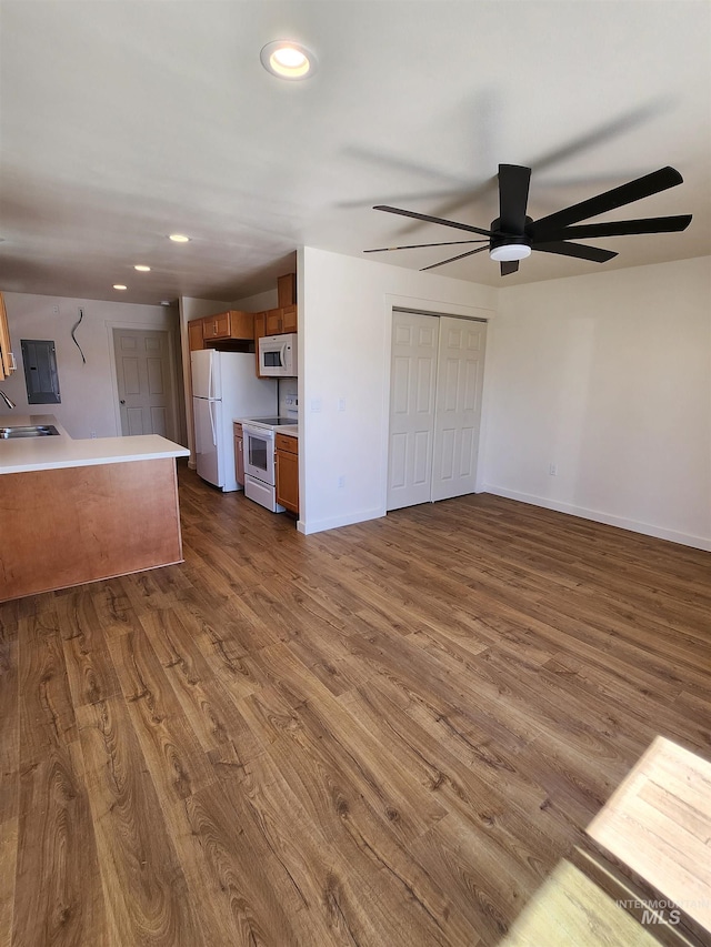 interior space with electric panel, ceiling fan, sink, and dark hardwood / wood-style flooring