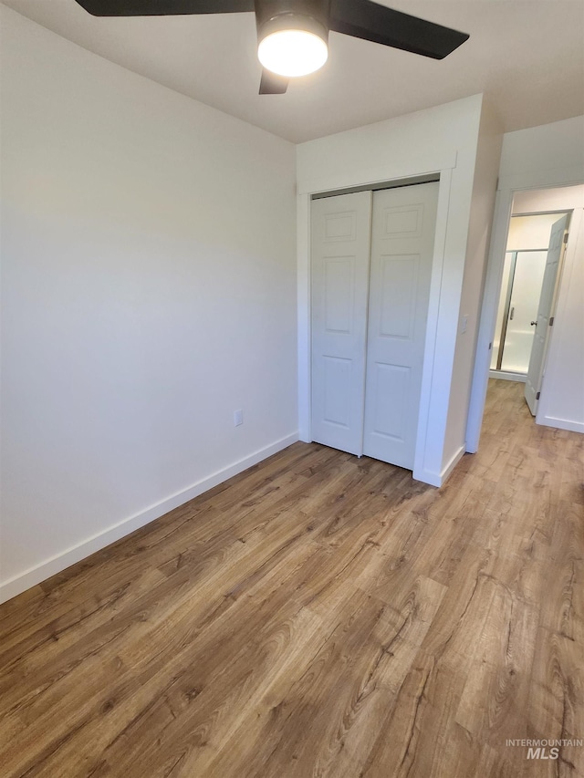 unfurnished bedroom with light wood-type flooring, ceiling fan, and a closet