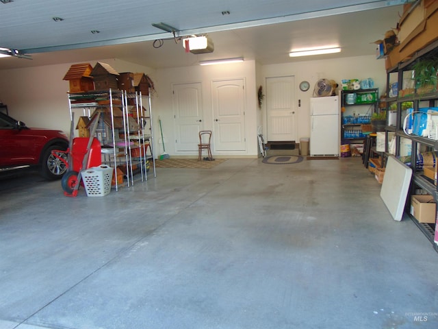 garage with a garage door opener and white fridge