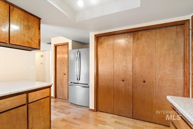 3493 N Buckboard Way, Boise, ID 83713 - kitchen with freestanding refrigerator, light countertops, brown cabinets, and light wood-style flooring