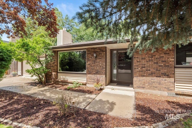 3493 N Buckboard Way, Boise, ID 83713 - entrance to property featuring brick siding, a chimney, and an attached garage