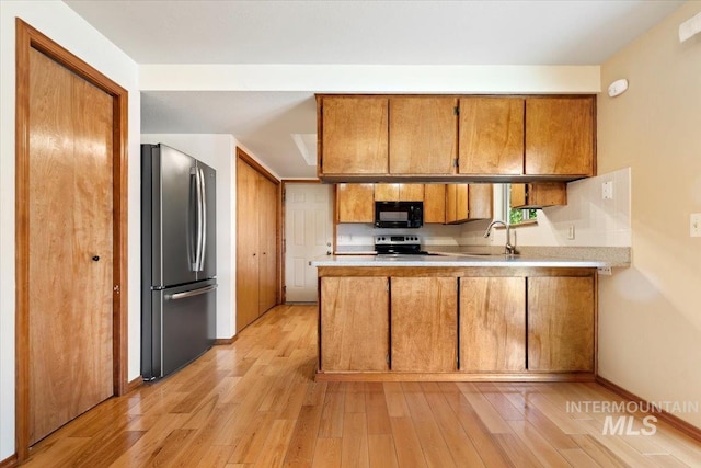 3493 N Buckboard Way, Boise, ID 83713 - kitchen featuring freestanding refrigerator, black microwave, brown cabinets, and a peninsula