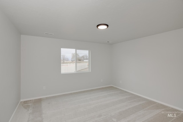 spare room with light colored carpet, visible vents, and baseboards