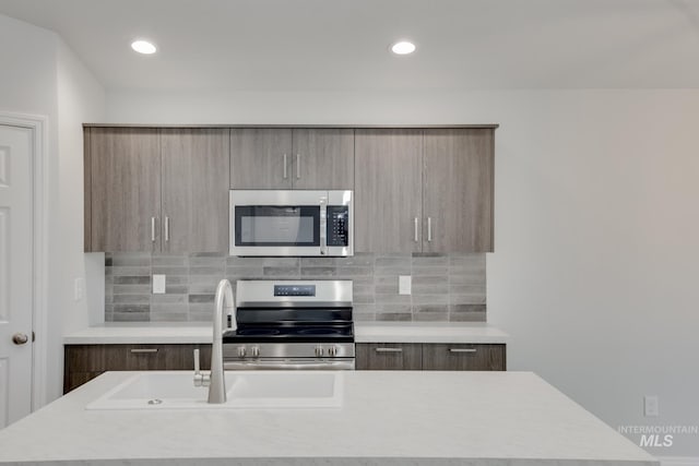 kitchen featuring backsplash, appliances with stainless steel finishes, modern cabinets, and light countertops