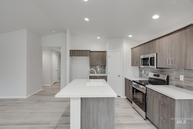 kitchen with appliances with stainless steel finishes, light countertops, lofted ceiling, and a sink