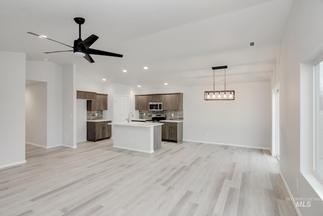 kitchen featuring a sink, decorative backsplash, light countertops, stainless steel appliances, and open floor plan