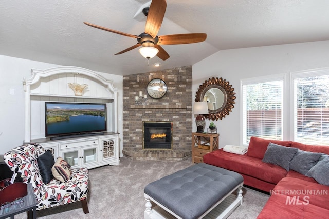 carpeted living room with lofted ceiling, ceiling fan, a textured ceiling, and a fireplace