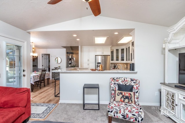 kitchen with high quality fridge, glass insert cabinets, vaulted ceiling with beams, a peninsula, and white cabinetry