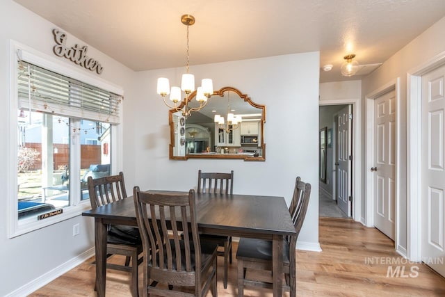 dining room featuring baseboards, an inviting chandelier, and light wood-style floors