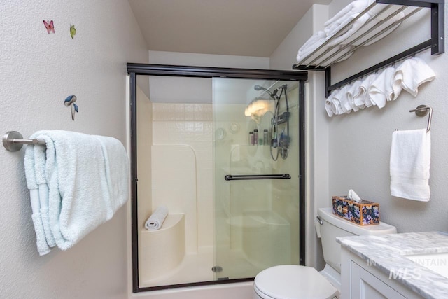 bathroom featuring a textured wall, vanity, a shower stall, and toilet