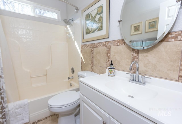 full bathroom featuring toilet, vanity, tile walls, wainscoting, and shower / bathtub combination with curtain