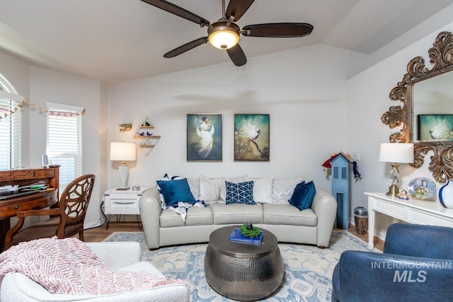 living area with vaulted ceiling, wood finished floors, and a ceiling fan