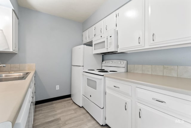 kitchen featuring white appliances, light wood-type flooring, light countertops, white cabinetry, and a sink