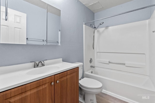 bathroom with vanity, a textured wall, wood finished floors, toilet, and  shower combination