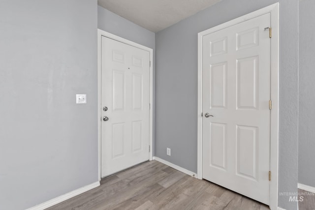 foyer entrance featuring baseboards and wood finished floors