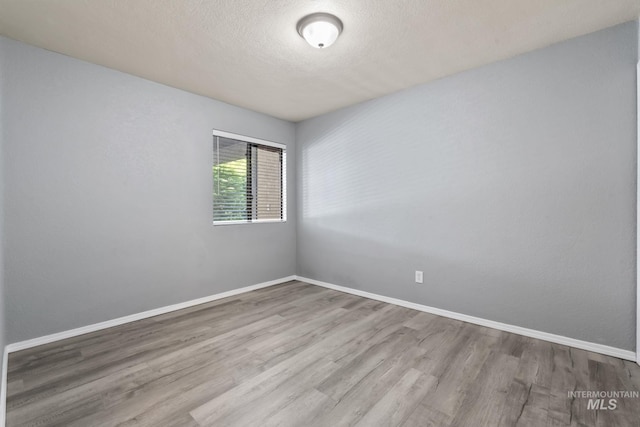 unfurnished room with baseboards, a textured ceiling, and wood finished floors