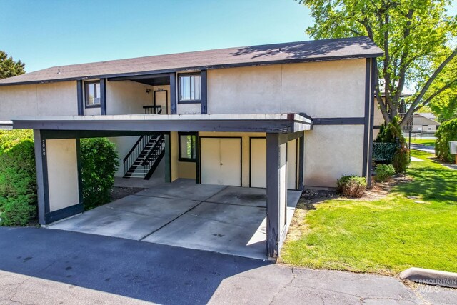 view of property featuring stairs, stucco siding, and a front yard