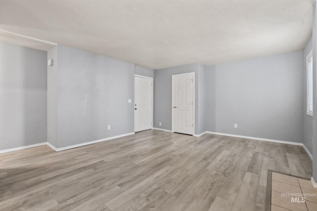 empty room with baseboards and light wood-style floors