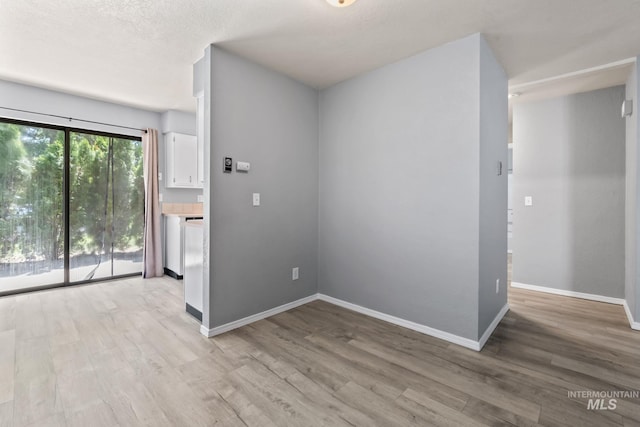 spare room featuring baseboards and light wood-style flooring