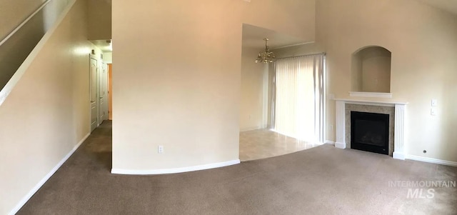 unfurnished living room featuring a chandelier, high vaulted ceiling, carpet, and a fireplace