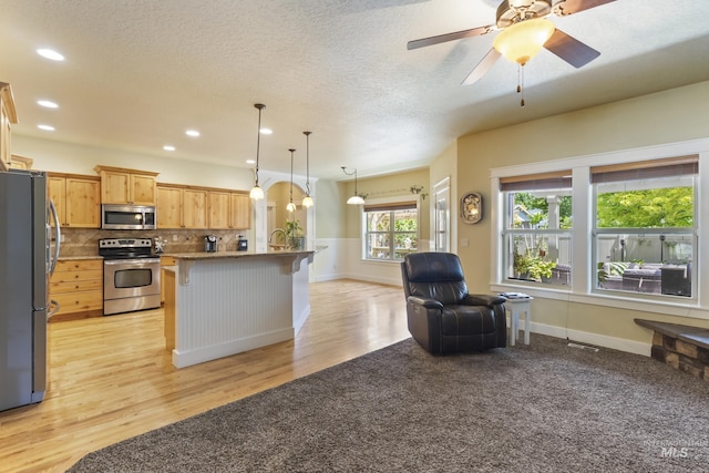 2310 W Herron Loop, Nampa, ID 83686 - kitchen featuring stainless steel appliances, a kitchen bar, light wood-style floors, open floor plan, and decorative backsplash