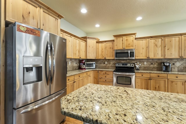 2310 W Herron Loop, Nampa, ID 83686 - kitchen with appliances with stainless steel finishes, light brown cabinetry, recessed lighting, decorative backsplash, and light stone counters